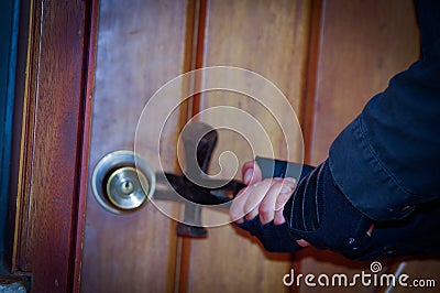 Close up of a burglar with crowbar trying break the door to enter the house Stock Photo