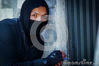 Close up a burglar wearing a mask holding a lock-picker to open a housedoor Stock Photo