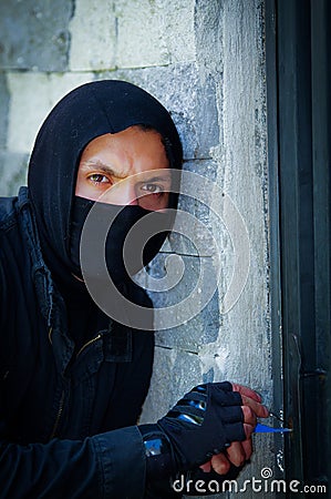 Close up a burglar wearing a mask holding a lock-picker to open a housedoor Stock Photo