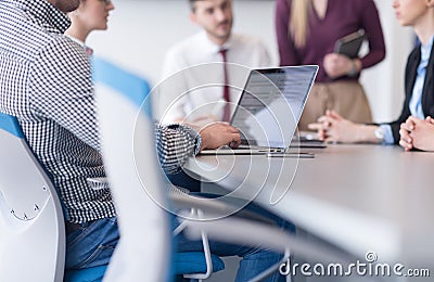 close up of business man hands typing on laptop with team on meeting in background Stock Photo