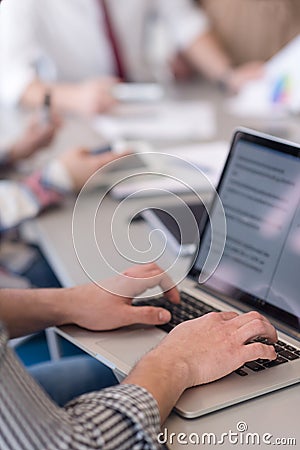 close up of business man hands typing on laptop with team on meeting in background Stock Photo