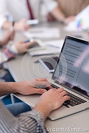 close up of business man hands typing on laptop with team on meeting in background Stock Photo