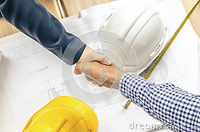Business people handshaking at background over helmets, documents, worker tool Stock Photo
