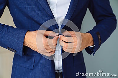 Close-up business stylish man buttoning his blue jacket, standing in a stylish office with designer repair. Stock Photo