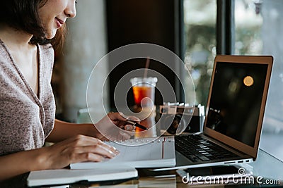 Close up of business woman`s hands using laptop and writing in her calendar notepad Stock Photo