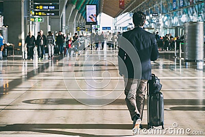 Close up of businessman carrying suitcase while walking through a passenger departure terminal in airport. Businessman traveler Editorial Stock Photo