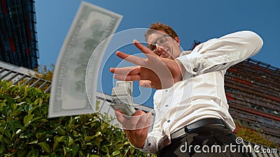 CLOSE UP: Businessman celebrates getting his first paycheck by making it rain. Stock Photo