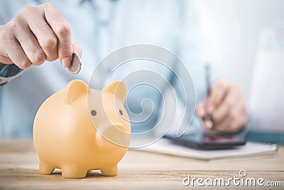 Close up businessman hand putting money coin into piggy for saving money, budget, investment or strategy for personal savings Stock Photo