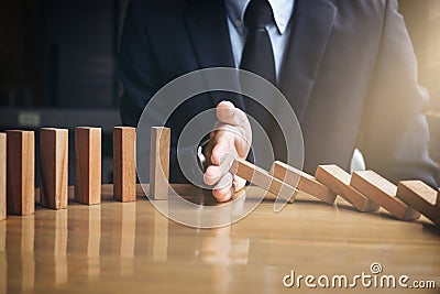 Close up of businessman hand Stopping Falling wooden Dominoes effect from continuous toppled or risk, strategy and successful int Stock Photo