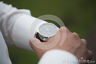 Close up of businessman looking at watch on his hand outdoors, free space. Man in white shirt checking time from luxury Stock Photo
