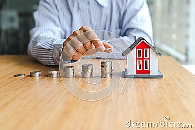 Close up businessman putting coin increase on coins stacking with house model Stock Photo