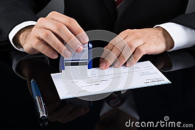 Businessman Stamping Cheque Stock Photo