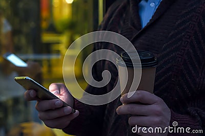 Close up of a businessman using mobile phone and holding paper cup. Close-up detail of a businessmans hand holding paper cup Stock Photo