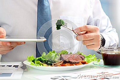 Close-up of businessman working on marketing strategy during business lunch, eating juicy club steak. Stock Photo