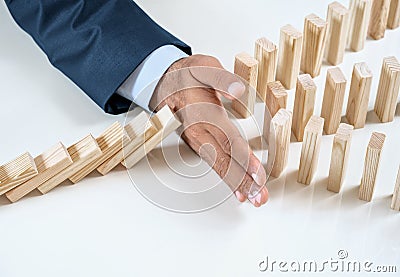 Close up of businessmans hand stopping the domino effect Stock Photo