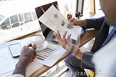 Close Up Of Businessmen Discussing Document In Coffee Shop Stock Photo