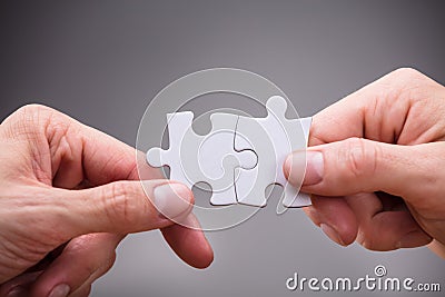 Close-up Of Businesspeople Holding Jigsaw Puzzle Stock Photo