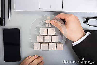 Businessperson Arranging Human Figure Cut Out On Wooden Blocks Stock Photo