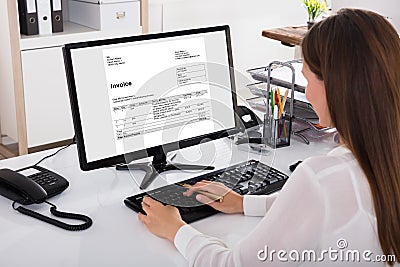 Businesswoman Looking At Invoice On Computer Stock Photo