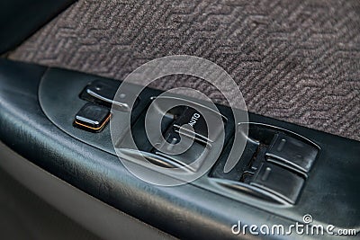 Close-up of buttons for electric adjustment of car windows on a black plastic panel with white signs on the door near the driver Stock Photo