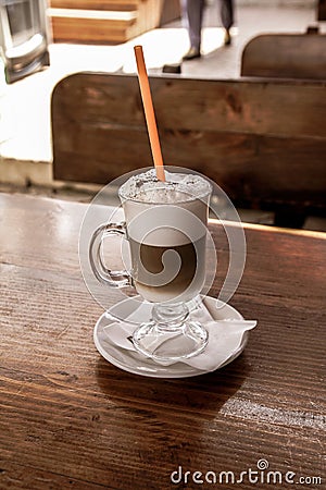 Close up of a cafe latte with a straw on a wooden table Stock Photo