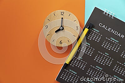 Close up of calendar, alarm clock and pen on the color table Stock Photo