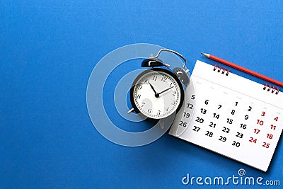 Close up of calendar, alarm clock, pencil on the blue table background Stock Photo