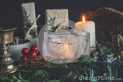 Close up of a candle burning in the ice. Festive Yule winter solstice Christmas set up on wiccan witch altar Stock Photo