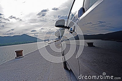 Close up of car door and mirror, pier, ocean, sky and mountain Stock Photo