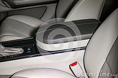 Close-up on the car front armrest with gray leather trim, buttons and seat belt in the interior after detailing Stock Photo