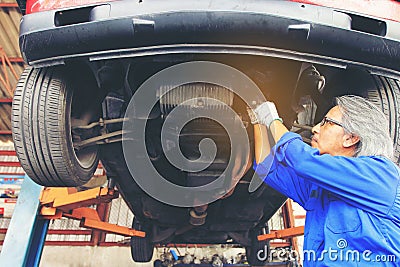 Close-up of car mechanic working under car in auto repair service. Stock Photo