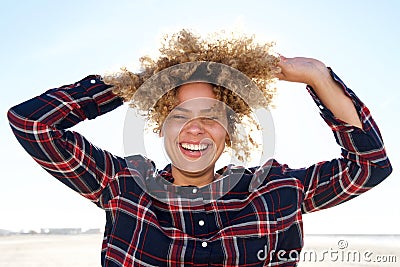 Close up carefree african american woman laughing with hands in hair outdoors Stock Photo