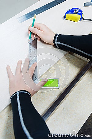 Close up Carpentry, mans hand using tape measure to measure wood plank and marking it with pencil. view from above Stock Photo