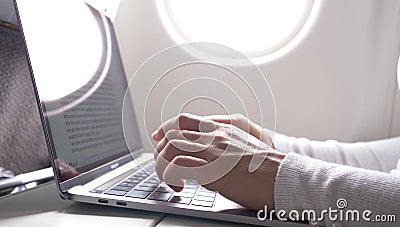 CLOSE UP: Caucasian female`s fingers type on sleek silver and black laptop keyboard during a long flight. Stock Photo