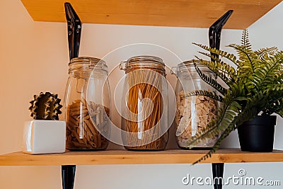 Close up of cereals in cans on shelf. Raw pasta products in glass jars in kitchen. Stock Photo