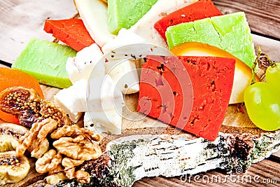 Close up of cheese plate - various types of cheese, honey, grapes, dried apricots, nuts and figs on a wooden cut. Stock Photo