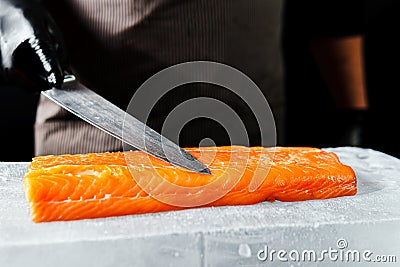 Close-up of chef hand prepared to cooking fresh salmon fillet, black background Stock Photo