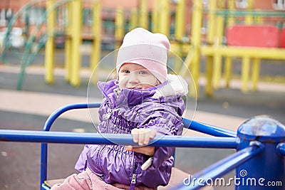 Close-up of a child of a girl sitting on a carousel on a playground Stock Photo