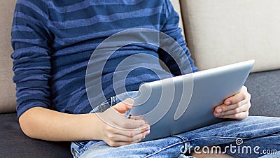 Close-up child hands with a tablet. Young boy playing game, reading book or checking social network on tablet Stock Photo