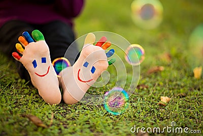 Close up of child human pair of feet painted with smiles outdoor in park with bubble Stock Photo