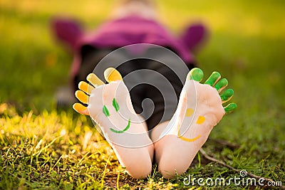 Close up of child human pair of feet painted with smiles outdoor in park Stock Photo