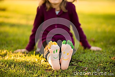 Close up of child human pair of feet painted with smiles outdoor in park Stock Photo