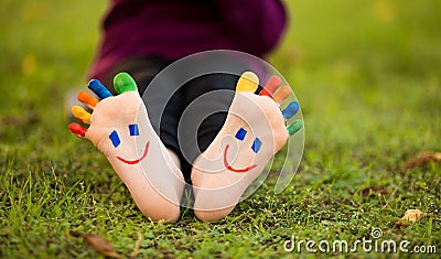 Close up of child human pair of feet painted with smiles outdoor in park Stock Photo