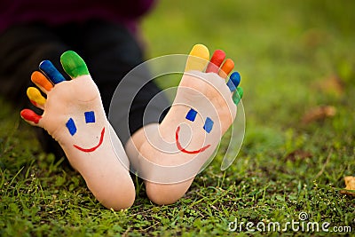 Close up of child human pair of feet painted with smiles outdoor in park Stock Photo