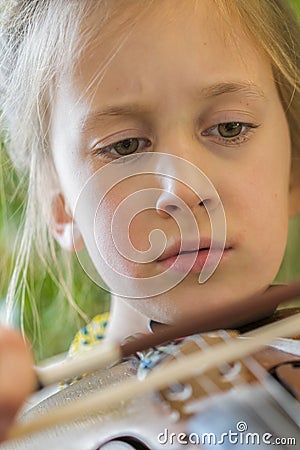 Close up of a child playing violin on green background. Portrait of girl with string and playing violin. Portrait of the little Stock Photo