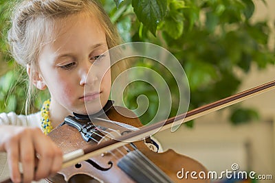 Close up of a child playing violin on green background. Portrait of girl with string and playing violin. Portrait of the little Stock Photo