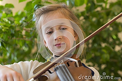 Close up of a child playing violin on green background. Portrait of girl with string and playing violin. Portrait of the little Stock Photo