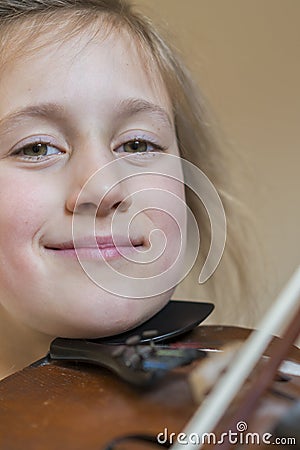 Close up of a child playing violin on isolated light background. Portrait of girl with string and playing violin. Portrait of the Stock Photo