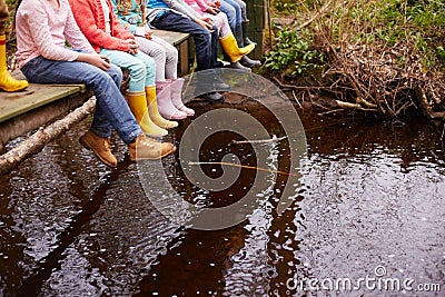 Close Up Of Children's Feet Dangling From Wooden Bridge Stock Photo