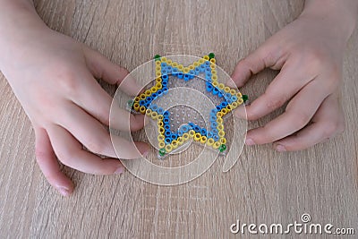 Close-up of children`s hands creating perler bead patterns, make crafts using thermomosaic technique, beading patterns, perler Stock Photo